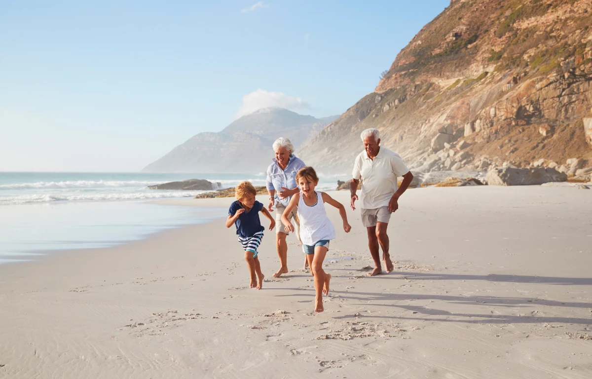 Grandparents playing with kids on beach